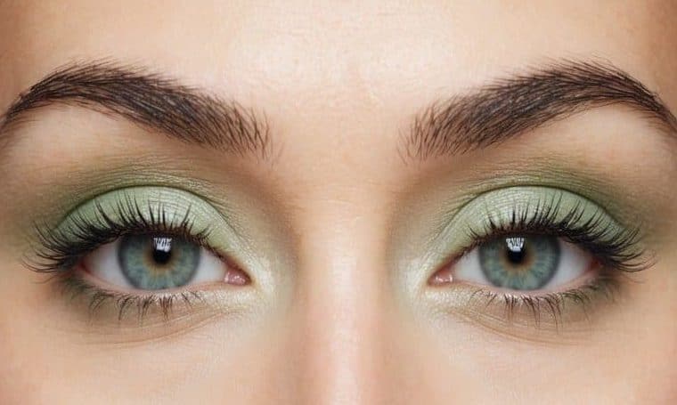 A close-up of a pair of eyes with soft, pastel green eye makeup, giving a refreshing and vibrant appearance