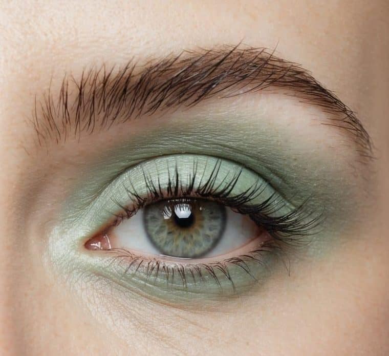 A close-up of pastel green eye makeup on a smooth, unblemished surface, with soft lighting to highlight the refreshing color