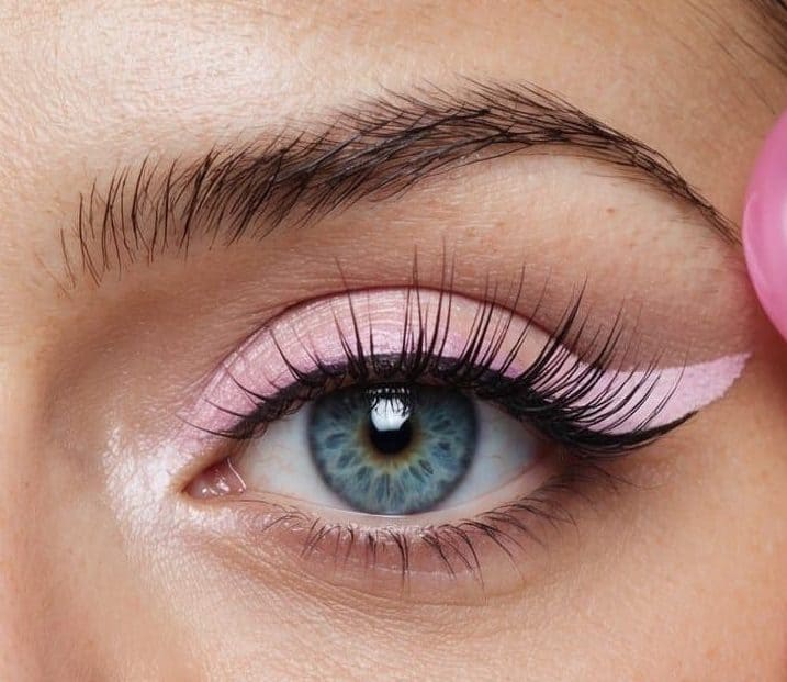 A close-up of a pair of eyes with pastel bubblegum pink eyeliner wings
