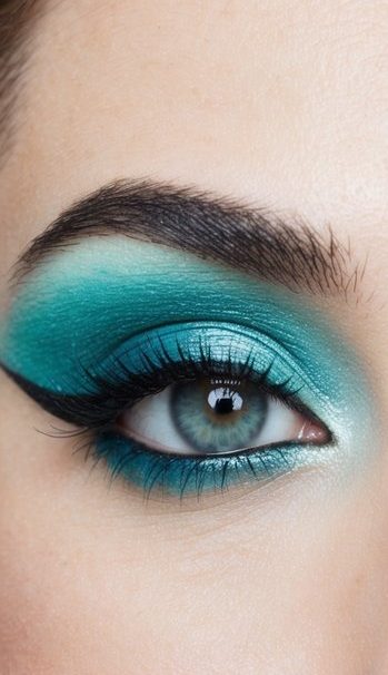 A close-up of a pair of bright aqua-colored eyes with shimmering eyeshadow and bold eyeliner, creating a refreshing and vibrant look