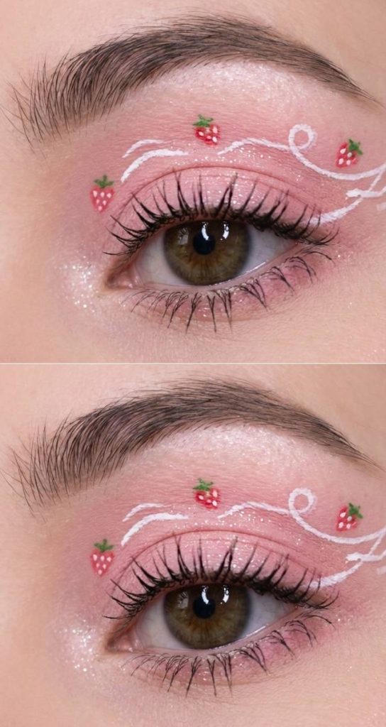 Eye with pastel pink eyeshadow, tiny strawberry designs, and swirling white liner for a sweet and playful take on crazy eye makeup looks.