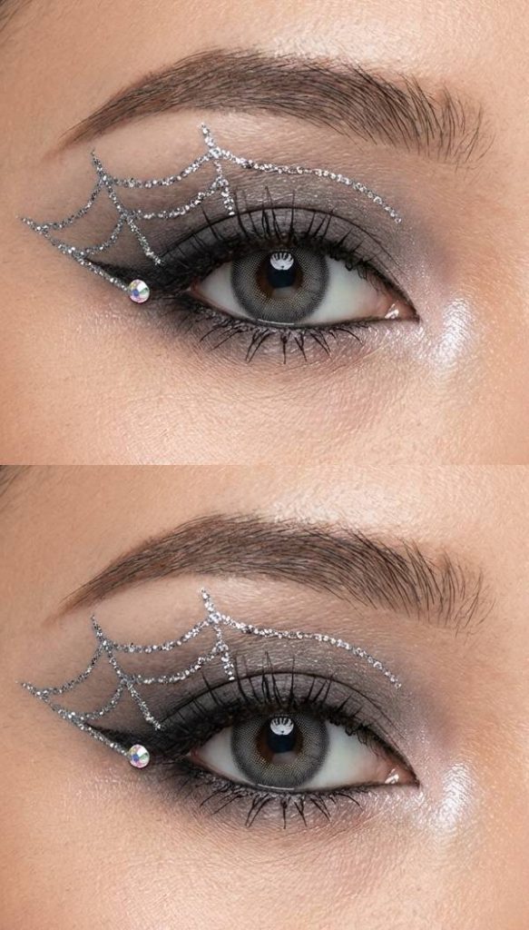 Detailed image of a spiderweb eye makeup idea using gradient cool-toned shadow, silver glitter webbing above the lid, and a gem at the eye's edge.