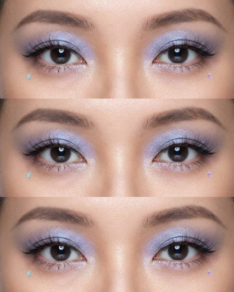 Close-up of douyin eye makeup trend featuring light lilac shimmer shadow, soft black lashes, and pastel-colored star stickers under the eyes.