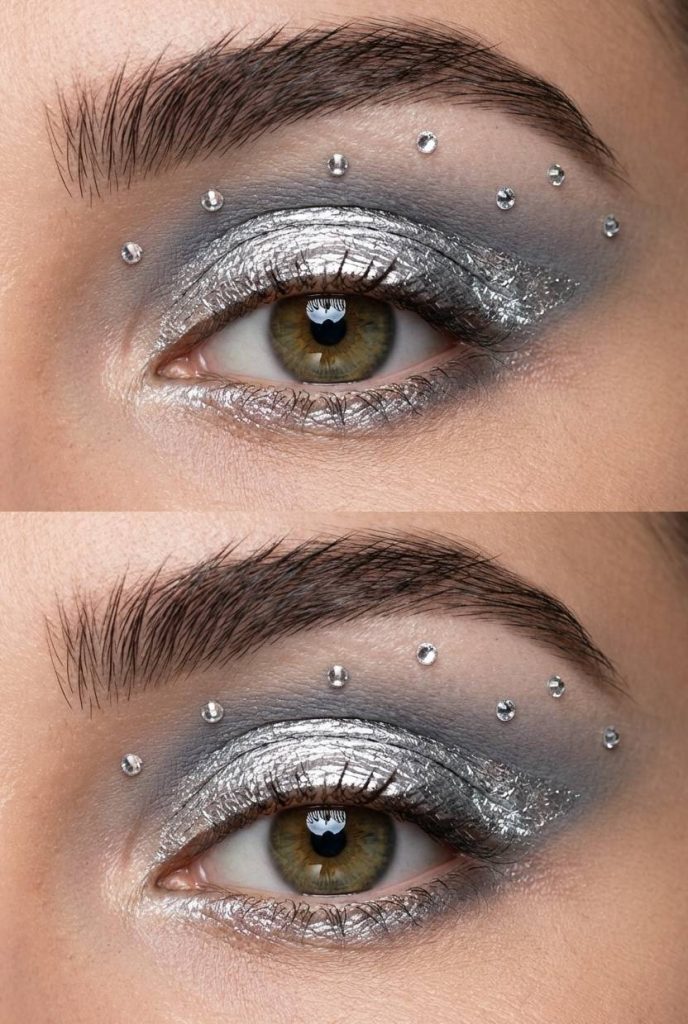 Rhinestone eye makeup idea with silver foil shadow and scattered crystals across the upper lid for a futuristic effect.