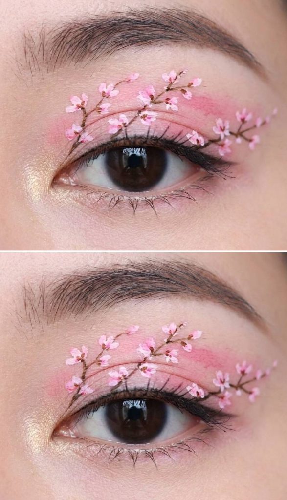 Eye makeup with delicate hand-painted cherry blossoms over pink shadow, showcasing a soft yet detailed take on crazy eye makeup looks.
