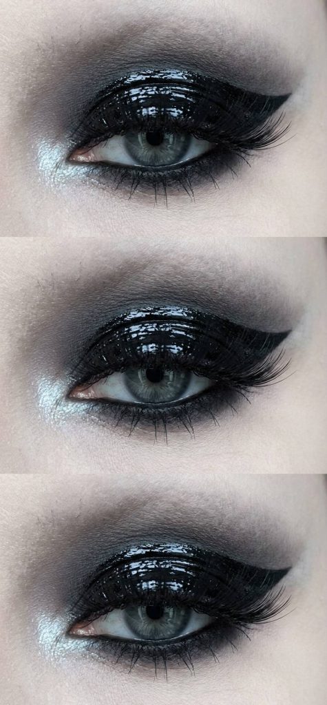 Close-up of a trad goth eye makeup look with glossy black eyelids, soft gray blending into the crease, and light-catching silver tear duct highlight.