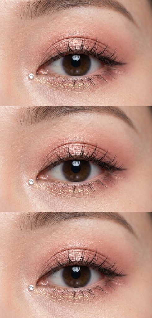 Close-up of douyin eye makeup trend with rose gold shimmer on the lids, golden shimmer below the lash line, and a small crystal near the outer corner.